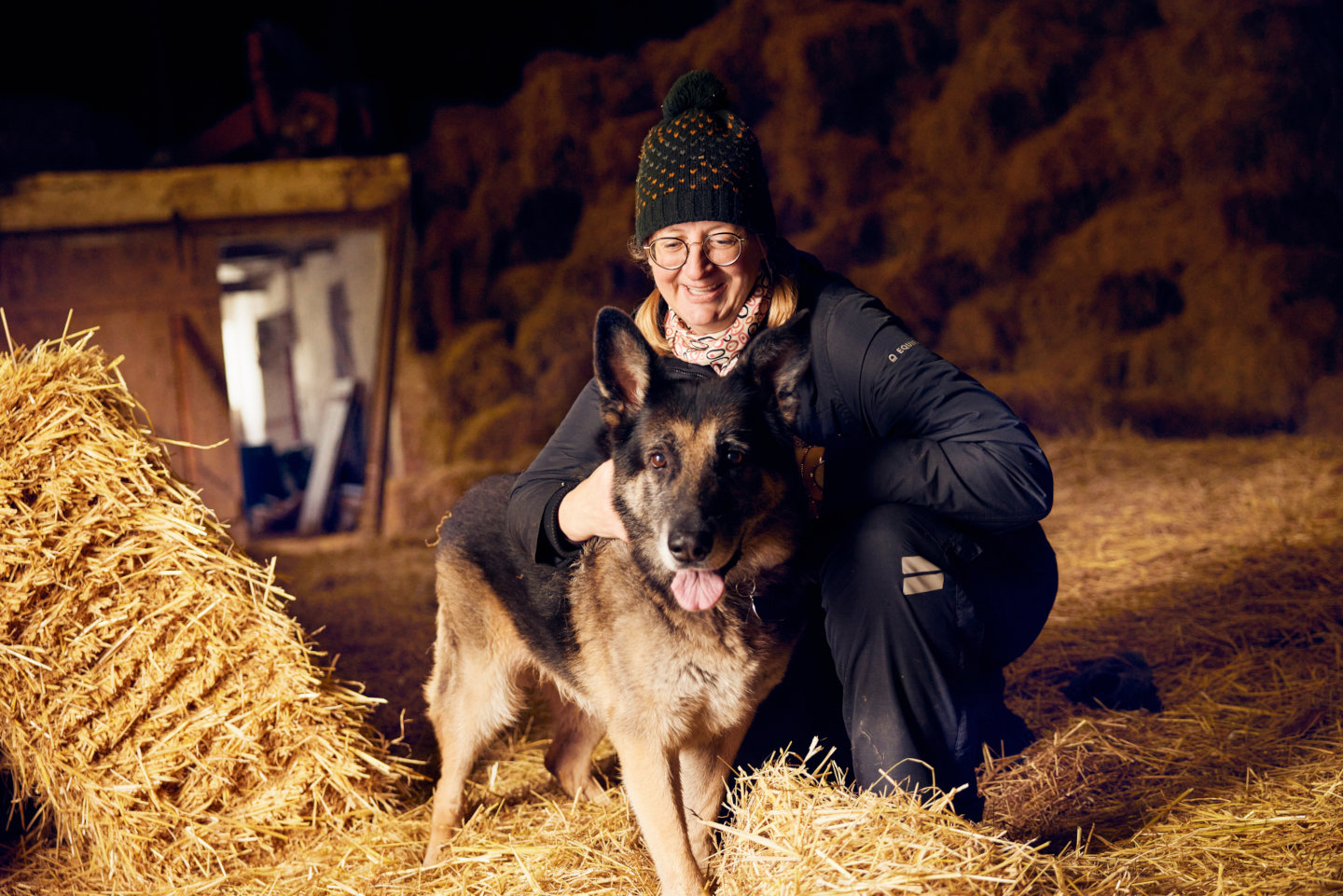 Marian petting her German Shepherd in the barn