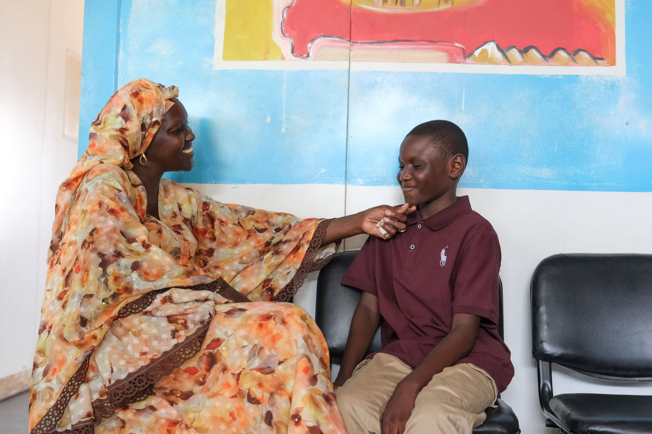 Photo of mother and son sitting in front of a colorful wall